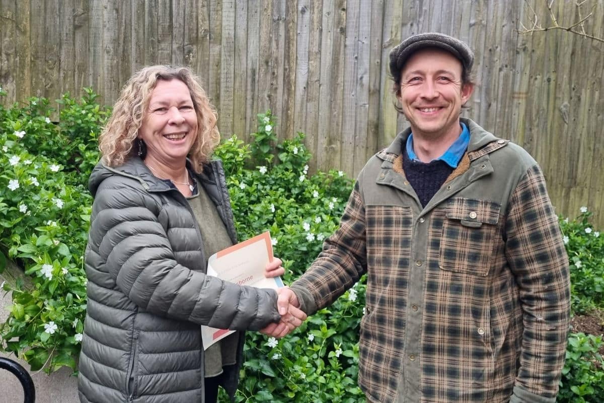 Woman and man shakings hands smiling and holding certificate